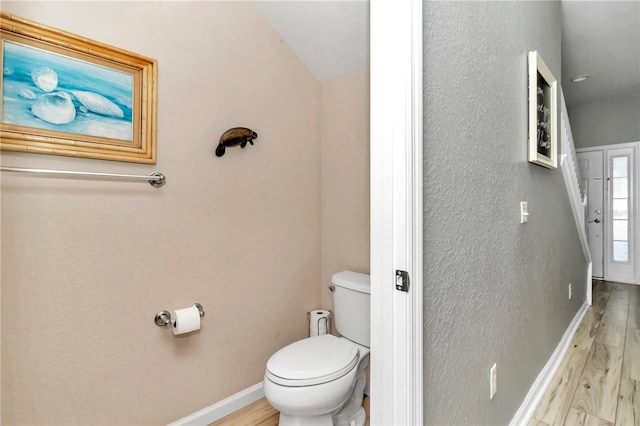 bathroom featuring toilet, wood-type flooring, and vaulted ceiling