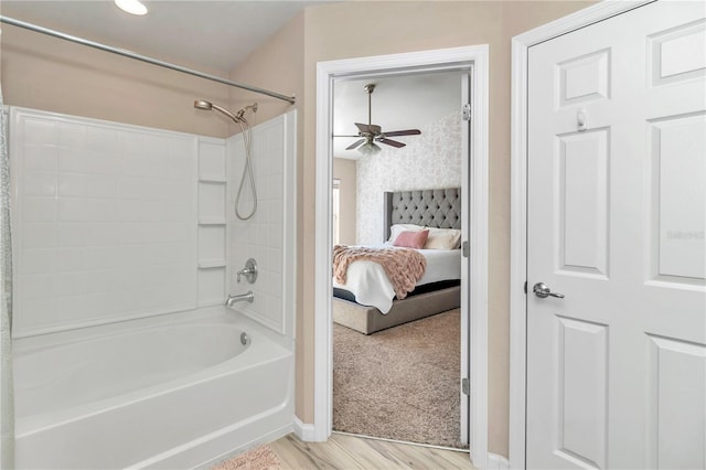 bathroom with hardwood / wood-style floors, ceiling fan, and bathing tub / shower combination