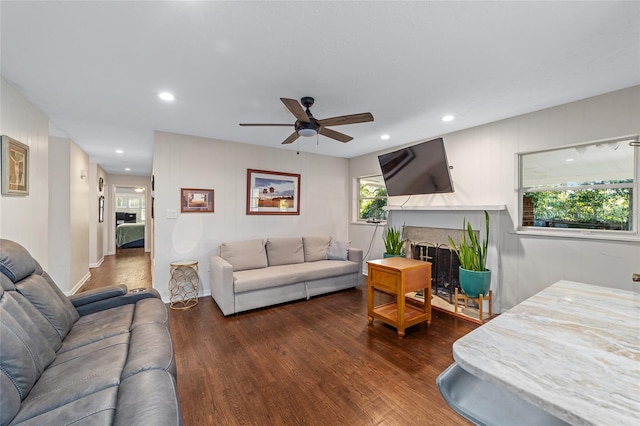 living room featuring plenty of natural light, ceiling fan, and dark wood-type flooring