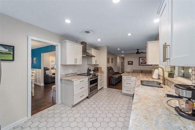 kitchen with wall chimney exhaust hood, double oven range, white cabinetry, and sink