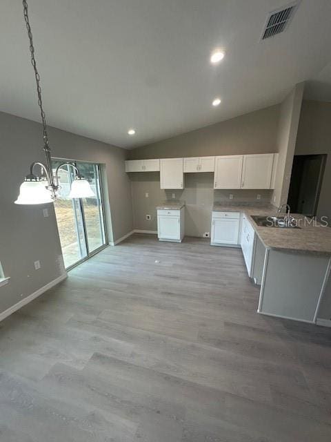 kitchen featuring lofted ceiling, hanging light fixtures, visible vents, and white cabinetry