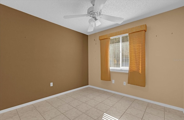 unfurnished room with ceiling fan, light tile patterned floors, and a textured ceiling