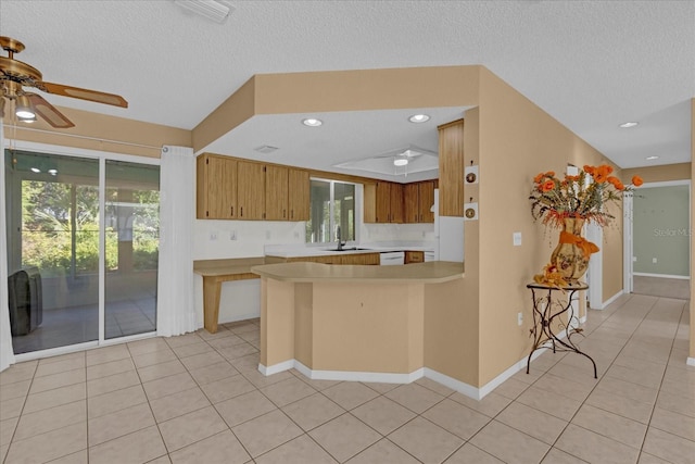 kitchen with kitchen peninsula, a textured ceiling, a wealth of natural light, and ceiling fan