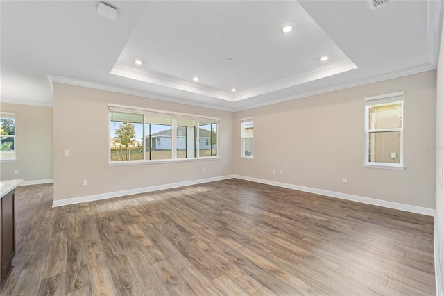 unfurnished room with a raised ceiling, ornamental molding, and light hardwood / wood-style flooring