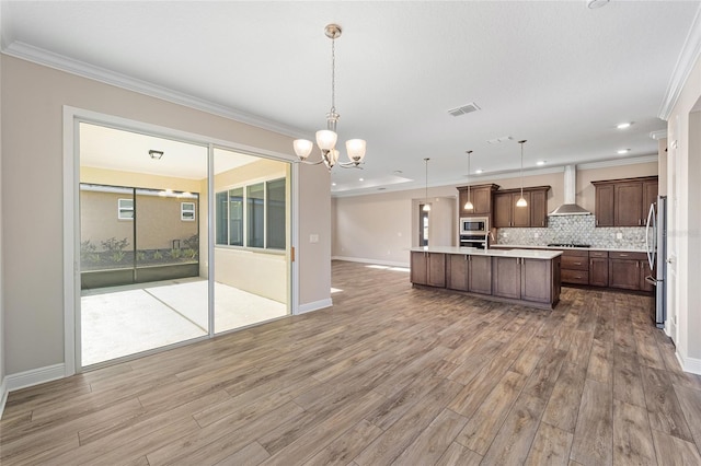 kitchen featuring pendant lighting, wall chimney exhaust hood, stainless steel appliances, and hardwood / wood-style flooring