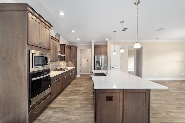 kitchen with pendant lighting, light wood-type flooring, stainless steel appliances, and a spacious island