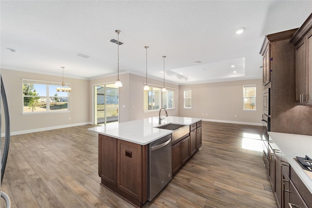 kitchen featuring appliances with stainless steel finishes, decorative light fixtures, a kitchen island with sink, and wood-type flooring