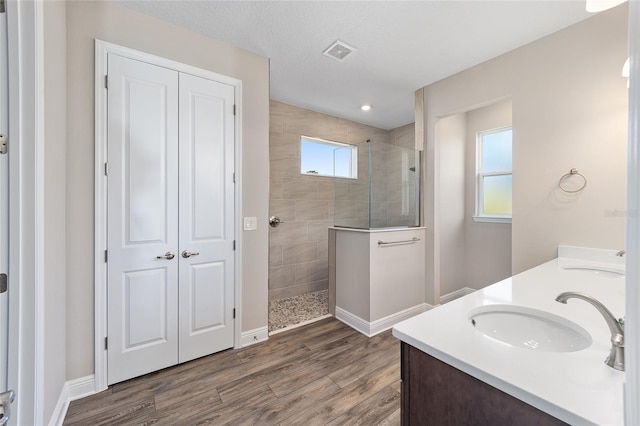 bathroom with vanity, a tile shower, wood-type flooring, and a textured ceiling