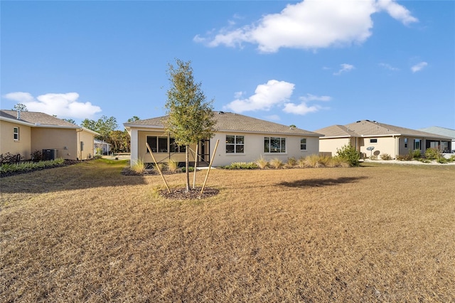 rear view of property with central AC and a lawn