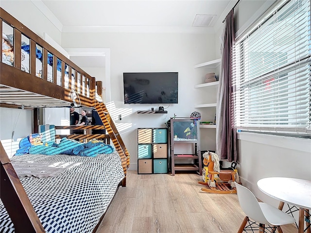 bedroom with crown molding and light hardwood / wood-style floors