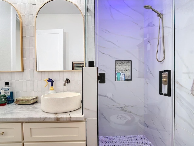 bathroom with vanity, tile walls, a shower with shower door, and backsplash