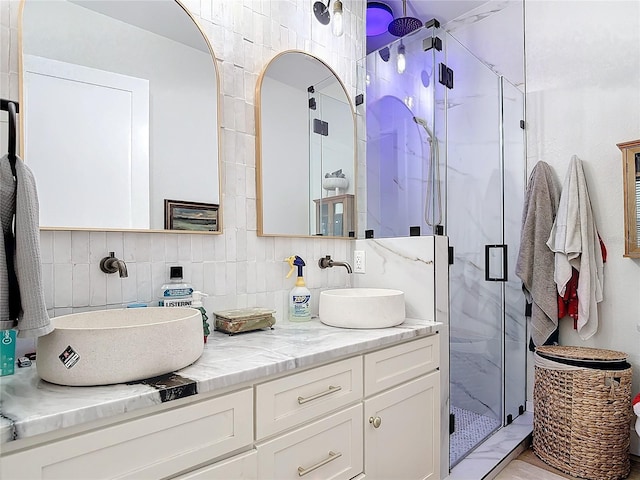 bathroom with vanity, tasteful backsplash, a shower with door, and tile walls