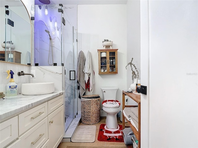 bathroom with backsplash, hardwood / wood-style floors, toilet, vanity, and a shower with shower door