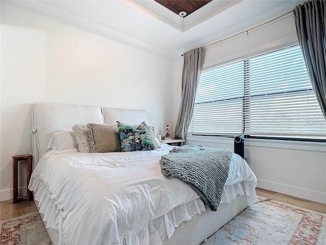 bedroom with a tray ceiling and light hardwood / wood-style floors