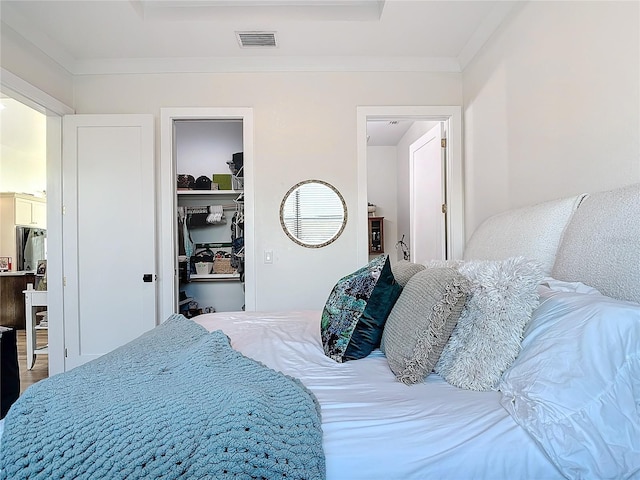 bedroom with stainless steel refrigerator, crown molding, a closet, and hardwood / wood-style floors