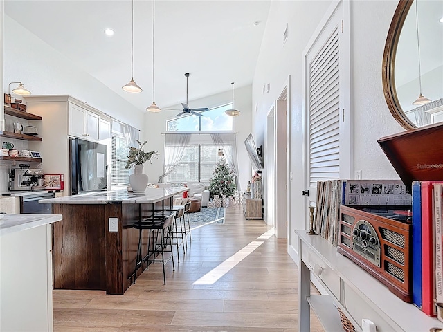 kitchen with white cabinets, pendant lighting, light wood-type flooring, and fridge