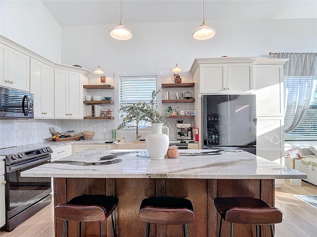 kitchen featuring a center island, black electric range, refrigerator, light hardwood / wood-style floors, and white cabinets