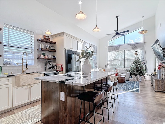 kitchen with white cabinets, refrigerator, a kitchen island, and decorative light fixtures