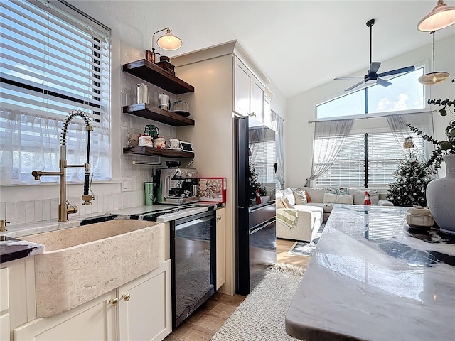 kitchen with light stone countertops, ceiling fan, sink, light hardwood / wood-style flooring, and white cabinetry