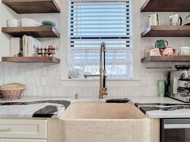 kitchen featuring tasteful backsplash, white cabinetry, and light stone countertops