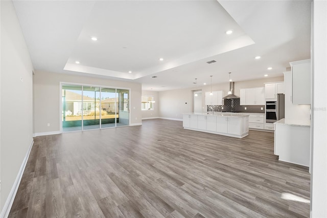 unfurnished living room with wood-type flooring and a tray ceiling