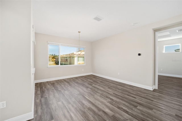 unfurnished room featuring dark hardwood / wood-style flooring and an inviting chandelier