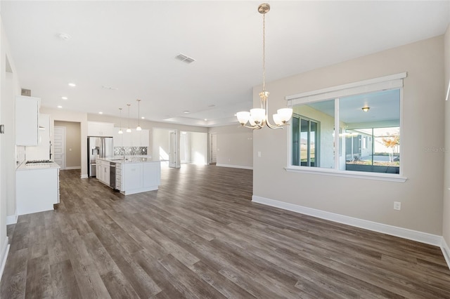 unfurnished living room featuring sink, dark wood-type flooring, and a chandelier