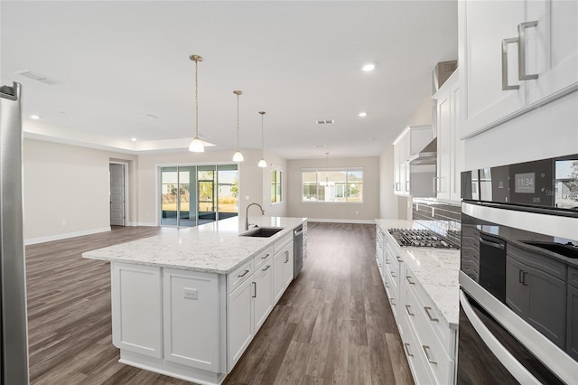 kitchen featuring dark hardwood / wood-style flooring, stainless steel appliances, sink, a center island with sink, and white cabinetry