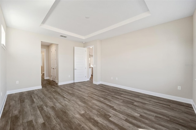 unfurnished room featuring dark hardwood / wood-style flooring and a tray ceiling