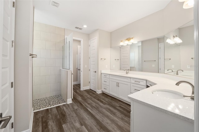 bathroom with hardwood / wood-style floors, vanity, and tiled shower