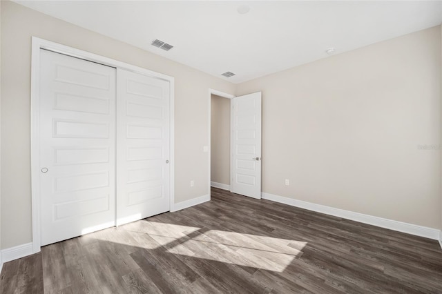 unfurnished bedroom with dark hardwood / wood-style floors and a closet