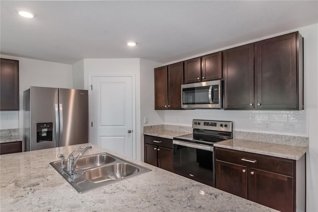 kitchen with dark brown cabinetry, sink, light stone countertops, and appliances with stainless steel finishes