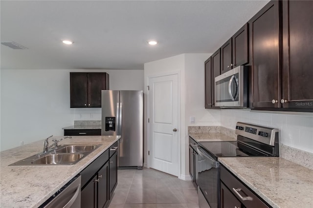 kitchen featuring sink, light tile patterned floors, appliances with stainless steel finishes, light stone counters, and dark brown cabinetry