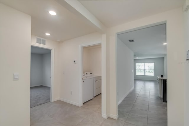 hall with independent washer and dryer and light tile patterned floors