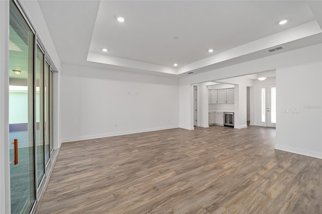 unfurnished living room with wood-type flooring and a tray ceiling