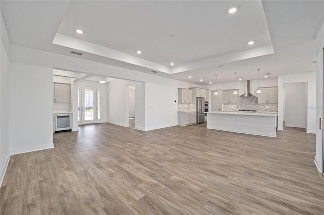 unfurnished living room with light hardwood / wood-style flooring and a tray ceiling