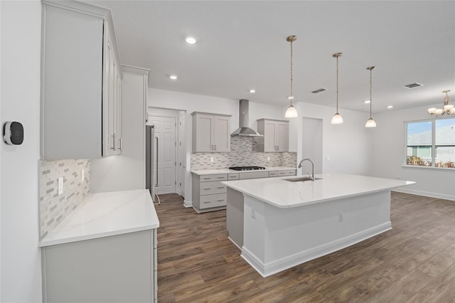 kitchen with a center island with sink, sink, wall chimney exhaust hood, dark hardwood / wood-style floors, and decorative light fixtures