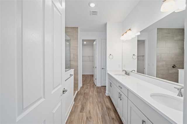 bathroom with vanity, wood-type flooring, and tiled shower