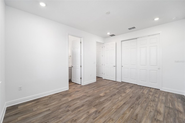 unfurnished bedroom with connected bathroom and dark wood-type flooring