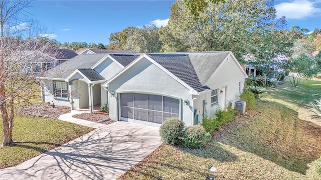 view of front of house featuring a front lawn, central AC unit, and a garage