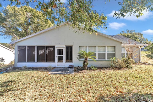 rear view of house featuring a lawn and a sunroom