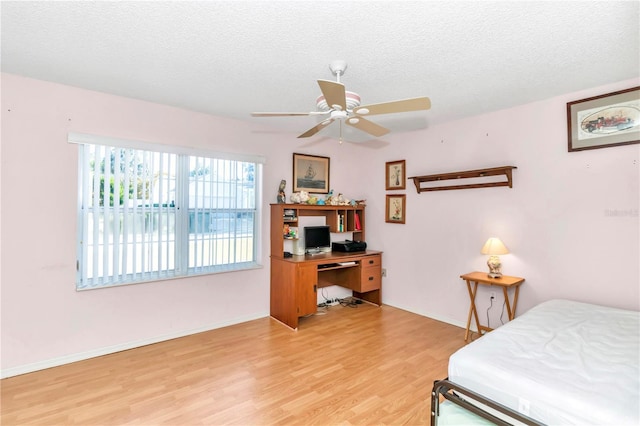 bedroom with a textured ceiling, light wood-type flooring, and ceiling fan