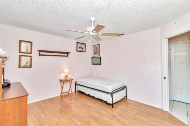 bedroom featuring ceiling fan, wood-type flooring, and a textured ceiling