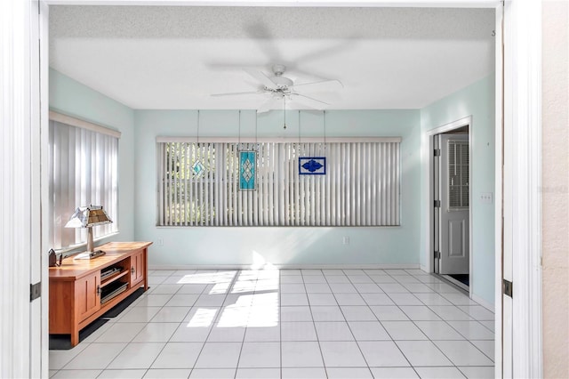 tiled spare room with a textured ceiling and ceiling fan