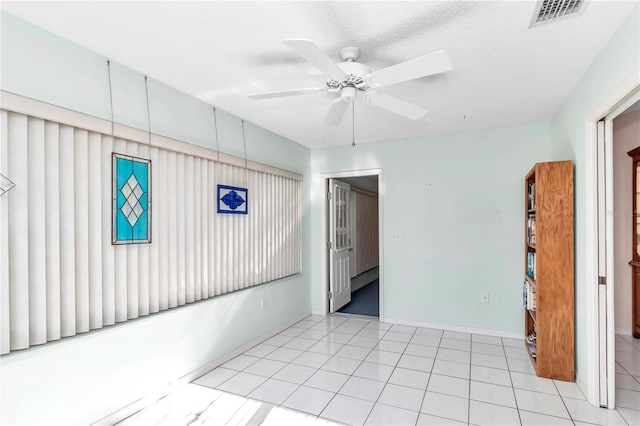 unfurnished room featuring ceiling fan, light tile patterned flooring, and a textured ceiling