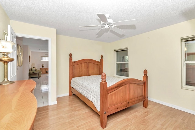 bedroom featuring ceiling fan, light hardwood / wood-style floors, and a textured ceiling