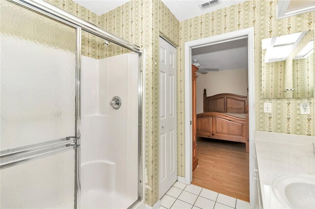 bathroom with vanity, a textured ceiling, ceiling fan, hardwood / wood-style floors, and a shower with shower door