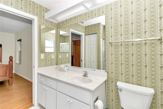 bathroom with toilet, vanity, a textured ceiling, and hardwood / wood-style flooring