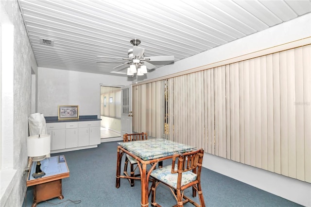 dining area with ceiling fan and dark carpet