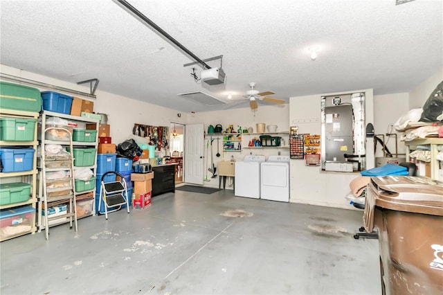 garage featuring heating unit, ceiling fan, washer and clothes dryer, sink, and a garage door opener